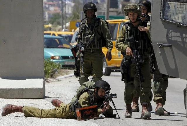 An Israeli soldier takes a position during clashes with Palestinian protesters following a protest marking Nakba Day near Israel's Hawra checkpoint near the West Bank city of Nablus May16, 2015. Palestinians marked “Nakba” (Catastrophe) on May 15 to commemorate the expulsion or fleeing of some 700,000 Palestinians from their homes in the war that led to the founding of Israel in 1948. (Photo by Abed Omar Qusini/Reuters)