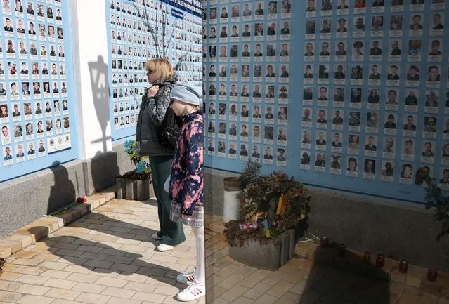 Local residents stand near the 'Wall of Remembrance of the Fallen for Ukraine', a wall with portraits of Ukrainian soldiers who died in the Russian-Ukrainian war in the centre of Kyiv on March 27, 2024, amid the Russian invasion of Ukraine. (Photo by Anatolii Stepanov/AFP Photo)