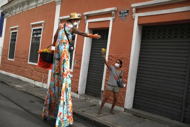 Anilson Costa, reveller of the annual block party “Ceu na Terra”, gives flowers to a woman to make people remember the block party in Santa Teresa neighborhood, as Carnival celebrations have been canceled, amid the coronavirus disease (COVID-19) pandemic, in Rio de Janeiro, Brazil on February 12, 2021. (Photo by Pilar Olivares/Reuters)