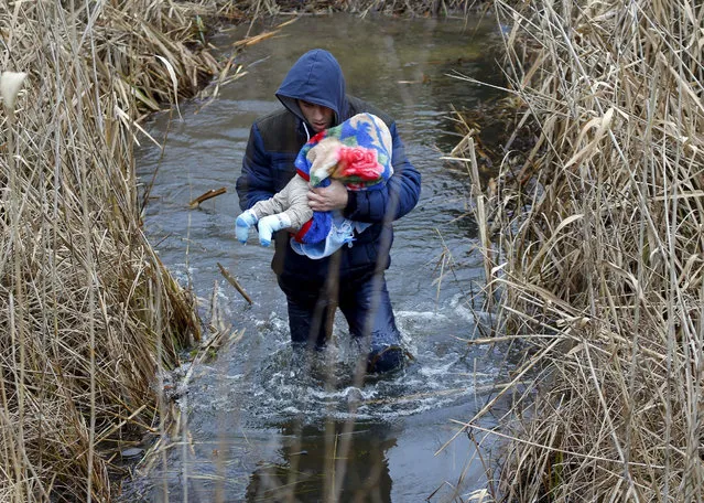 A Kosovar man wades through the water while carrying his child as they illegally cross the Hungarian-Serbian border near the village of Asotthalom, Hungary in this February 6, 2015 file photo.  Hungary announced plans on Wednesday to build a four-meter-high fence along its border with Serbia to stem the flow of illegal migrants, in a move likely to annoy human rights groups and the European Union. The landlocked central European country of 10 million people is in the EU's visa-free Schengen zone and thus an attractive destination for tens of thousands of migrants entering Europe through the Balkans from the Middle East and beyond.   REUTERS/Laszlo Balogh/Files