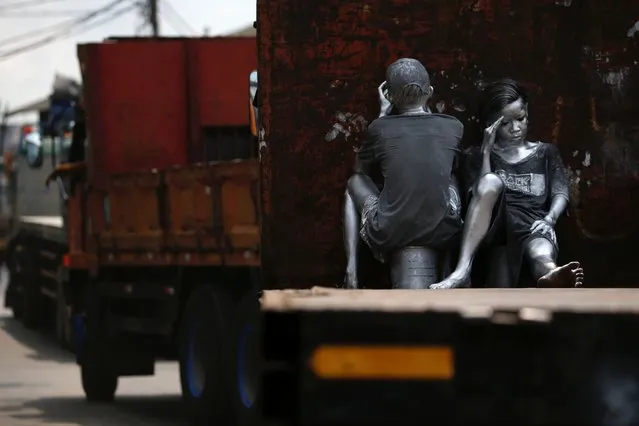 Youths, who covered themselves from head to toe in silver paint to become “manusia silver” (silvermen), as part of their act to make a living, ride on the back of a truck in Jakarta, Indonesia, March 31, 2021. (Photo by Willy Kurniawan/Reuters)