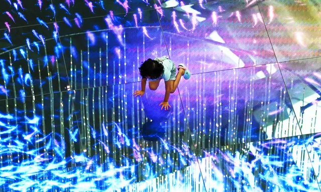 A child plays with an animated projected lights installation at a shopping mall in Singapore on May 14, 2021. (Photo by Roslan Rahman/AFP Photo)