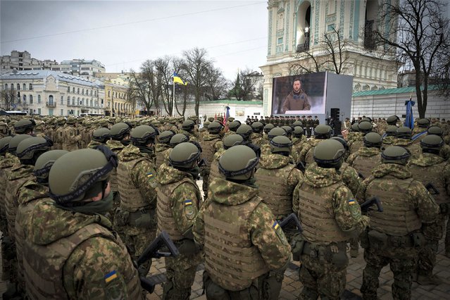 This handout picture taken and released by Ukrainian Presidential press service on February 24, 2023, shows Ukrainian servicemen and servicewomen attending a ceremony with Ukrainian President Volodymyr Zelensky shown on a screen at St Sophia Square in Kyiv, on the first anniversary of the Russian invasion of Ukraine. (Photo by Handout/Ukrainian Presidential Press Service via AFP Photo)