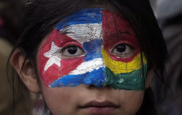 A girl with Cuban and Bolivian flag colors painted on her face takes part in a march in support of the Cuban government, near the U.S. embassy in La Paz, Bolivia, Wednesday, July 14, 2021. The march came about after a weekend of rare protests across Cuba over high prices, food shortages and power outages, while some people also called for a change in the government. (Photo by Juan Karita/AP Photo)