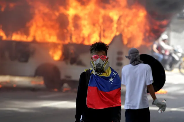 Demonstrators stand next to a bus burns near a protest against Venezuela's President Nicolas Maduro's government in Caracas, Venezuela, May 13, 2017. (Photo by Christian Veron/Reuters)