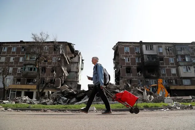 A local resident walks past an apartment building damaged during Ukraine-Russia conflict in the southern port city of Mariupol, Ukraine on April 19, 2022. (Photo by Alexander Ermochenko/Reuters)