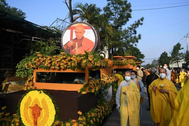 Buddhist followers walk by the convoy carrying the coffin of Vietnamese monk Thich Nhat Hanh,one of the world's most influential and prominent religious leaders, to a cremation site in Hue province on January 29, 2022. (Photo by Nhac Nguyen/AFP Photo)