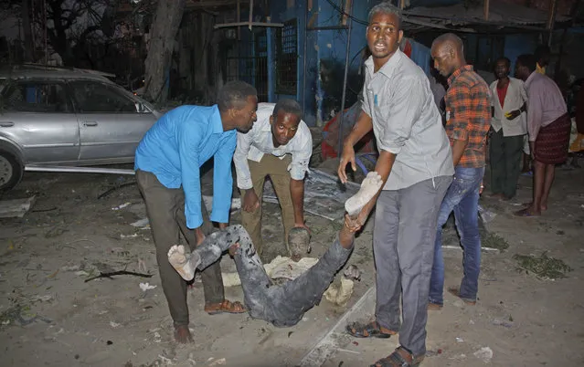 Somali men carry a wounded civilian who was injured in a bomb attack on an hotel in Mogadishu, Somalia Wednesday, June 1, 2016. The attack took place on the Ambassador hotel, which is often frequented by government officials and business executives. (Photo by Farah Abdi Warsameh/AP Photo)