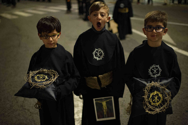 Young penitents from the “Silencio del Santisimo Cristo del Rebate” brotherhood react while taking part in a Holy Week procession in Tarazona, northern Spain, Tuesday, April 12, 2022. Hundreds of processions take place throughout Spain during the Easter Holy Week after two years due to the coronavirus pandemic. (Photo by Alvaro Barrientos/AP Photo)
