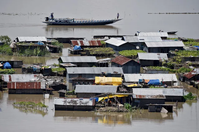 Villagers use a boat as they row past partially submerged houses at a flood-affected village in Morigaon district in the northeastern state of Assam, India July 14, 2017. The floods caused by torrential rains across the hilly states of Assam, Arunachal Pradesh, Nagaland and Manipur over the past two weeks, have triggered landslides and killed at least 83 people. In all more than 2 million people have been displaced, authorities say. (Photo by Anuwar Hazarika/Reuters)