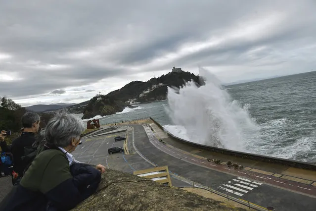 People look at a giant wave crashing against the sea defenses, during a high tide in San Sebastian, northern Spain, Sunday, December 22, 2019. Spain experienced high winds and heavy rain as a storm reached the northern Iberian Peninsula from the Atlantic. (Photo by Alvaro Barrientos/AP Photo)