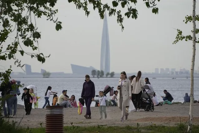 People walk along the coast of the Gulf of Finland in St. Petersburg, Russia, Wednesday, June 1, 2022, with the Business Tower Lakhta Centre, the headquarters of Russian gas monopoly Gazprom in the background. As Russia's military operation in Ukraine is entering its 100-day anniversary, life in Moscow and St. Petersburg remains largely normal, even as many Western retailers have left Russia. (Photo by Dmitri Lovetsky/AP Photo)