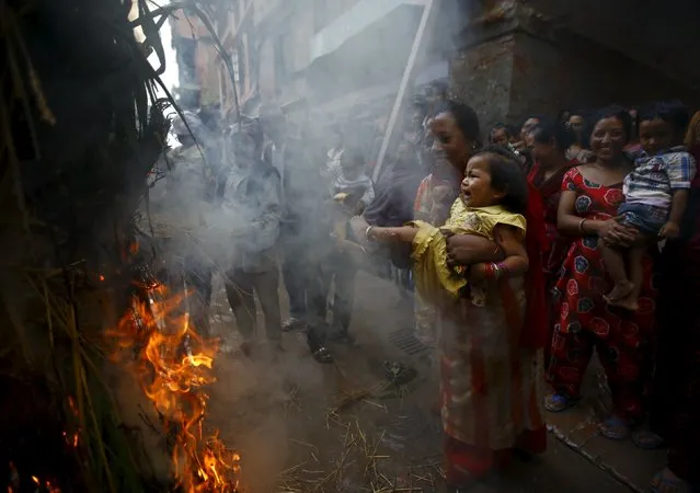 A woman swings a child around a fire, where an effigy of the demon Ghantakarna was burnt to symbolize the destruction of evil, during the Ghantakarna festival at the ancient city of Bhaktapur, Nepal August 12, 2015. (Photo by Navesh Chitrakar/Reuters)