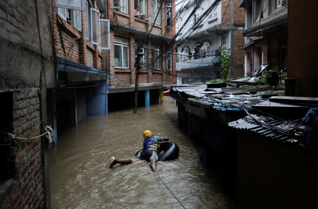 A security force member uses an inflated tube as he heads to rescue residents stranded in the flooded area near the bank of the overflowing Bagmati River following heavy rains, in Kathmandu, Nepal on September 28, 2024. (Photo by Navesh Chitrakar/Reuters)