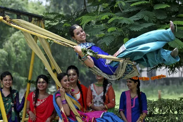 Traditionally dressed girls play on swings during the Teej festival in Chandigarh, India, August 17, 2015. Teej falls in the Hindu month of Shrawan (July-August) and welcomes the advent of the monsoon. (Photo by Ajay Verma/Reuters)