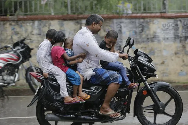 An Indian man rides a motorcycle carrying four children in the rain in Allahabad, India, Tuesday, July 5, 2016. Monsoon season in India begins in June and ends in October. (Photo by Rajesh Kumar Singh/AP Photo)