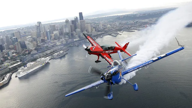 Pilots John Klatt, right, flying the blue Air National Guard MX-S airplane, and Jeff Boerboon, left, flying the red Jack's Links Extra 300L airplane, fly in formation Saturday, August 2, 2014, above Seattle. The two will perform Saturday and Sunday as part of the Boeing Seafair Air Show. (Photo by Ted S. Warren/AP Photo)