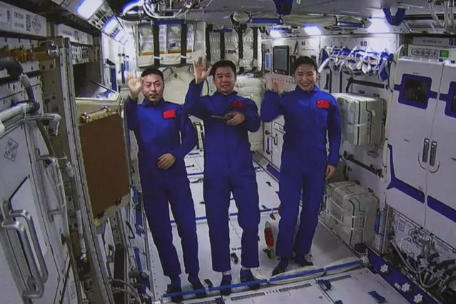 In this photo released by Xinhua News Agency, an image taken off the screen at the Beijing Aerospace Control Center shows Chinese astronauts from left, Cai Xuzhe, Chen Dong and Liu Yang wave from inside the Wentian lab module on Monday, July 25, 2022. China added the laboratory to its permanent orbiting space station Monday as it moves toward completing the structure in coming months. (Photo by Guo Zhongzheng/Xinhua via AP Photo)