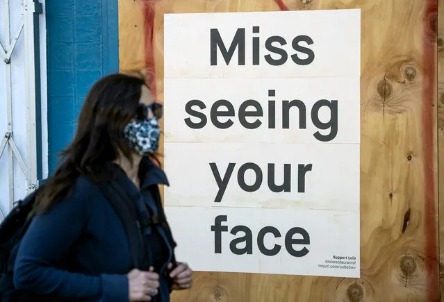 A woman in a face mask walks by a sign posted on a boarded up restaurant in San Francisco, California on April, 1, 2020, during the novel coronavirus outbreak. The US death toll from the coronavirus pandemic topped 5,000 late on April 1, according to a running tally from Johns Hopkins University. (Photo by Josh Edelson/AFP Photo)