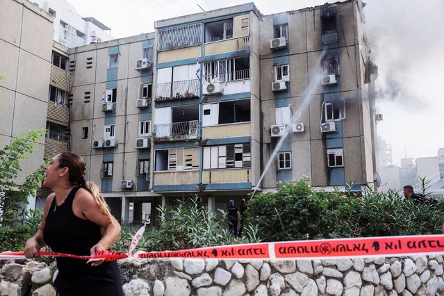 A woman calls out as smoke rises from a residential apartment building where a rocket hit, that was fired from the Gaza Strip towards Israel, in Tel Aviv, Israel on October 27, 2023. (Photo by Itai Ron/Reuters)