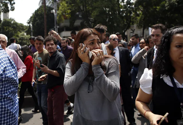 A woman speaks on her cell phone as people evacuated from office building gather in Reforma Avenue after an earthquake in Mexico City, Tuesday September 19, 2017. A powerful earthquake jolted central Mexico on Tuesday, causing buildings to sway sickeningly in the capital on the anniversary of a 1985 quake that did major damage. (Photo by Rebecca Blackwell/AP Photo)