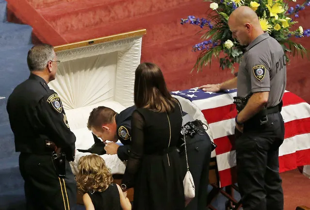 Oklahoma City police officer Sgt. Ryan Stark, center, leans over the casket of his canine partner, K-9 Kye, following funeral services for the dog in Oklahoma City, Thursday, August 28, 2014. K-9 Kye, a three year old Belgian German Shepard, died Aug. 25 after being stabbed by a burglary suspect on Aug. 24. Sgt. Stark tried to separate the dog and the suspect before fatally shooting the suspect. (Photo by Sue Ogrocki/AP Photo)