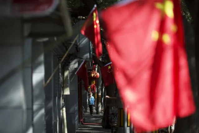 A woman walks under Chinese flags decorating a hutong in central Beijing September 2, 2015 as people in the capital prepares to mark the end of World War Two. (Photo by Damir Sagolj/Reuters)
