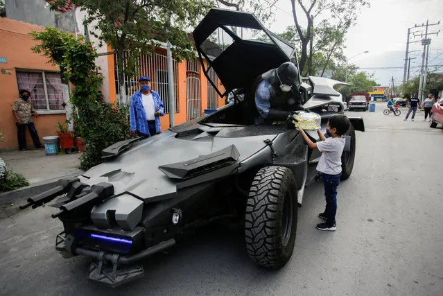 Mexican lawyer Candelario Maldonado, dressed up as the fictional character Batman, gives a birthday cake to a child wearing face mask in front of his home, during the global outbreak of the coronavirus disease (COVID-19), in Monterrey, Mexico on April 18, 2020. (Photo by Daniel Becerril/Reuters)