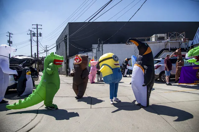The T-Rex Walking Club, a group of people that gather in a variety of inflatable costumes meet in the parking lot of Elks Lodge before heading out to parade through neighborhoods in hopes of cheering up the community during the COVID-19, coronavirus in Ferndale, Michigan, on April 27, 2020. (Photo by Emily Elconin/AFP Photo)