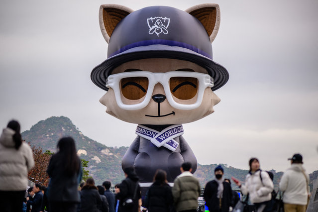 People walk in front of a huge temporarily installed “Teemo” at the “2023 Worlds Fan Fest” for the League of Legends World Championship 2023, also known as LoL Worlds 2023 or Worlds 2023, at Gwanghwamun Square in Seoul on November 17, 2023, ahead of the grand final on November 19. The LoL season will culminate in a best of five match between South Korea's T1 and Chinese team Weibo Gaming at the sold 18,000-seat Gocheok Sky Dome in western Seoul on November 19. (Photo by Anthony Wallace/AFP Photo)