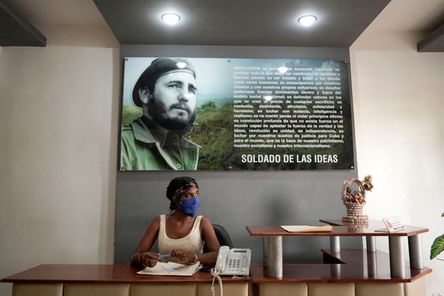 Rosibel Toledano, 20, talks to a visitor (not pictured) under an image of late Cuban President Fidel Castro in a state building amid concerns about the spread of the coronavirus disease (COVID-19) outbreak, in Zaragoza, Cuba, April 28, 2020. (Photo by Alexandre Meneghini/Reuters)