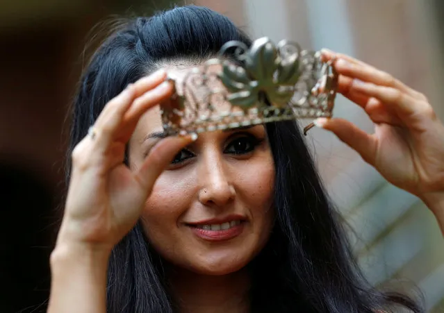 Syrian refugee Ninorta Bahno holds a crown during the preparation for the crowning ceremony to the Trier wine queen in Trier, Germany, August 3, 2016. (Photo by Ralph Orlowski/Reuters)