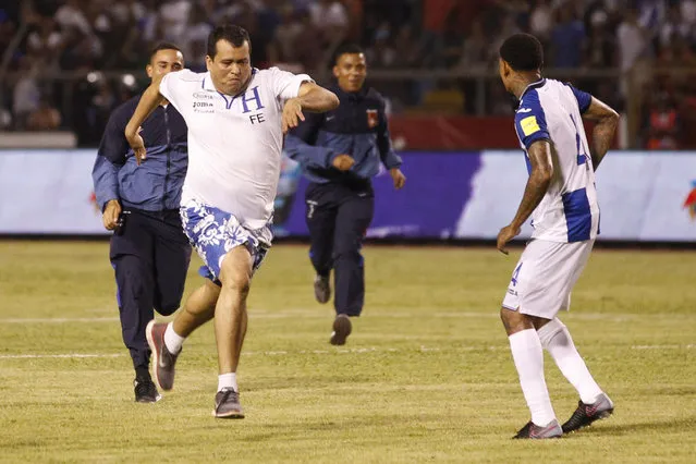 A Honduras fan is chased by security guards after he invaded the pitch during a World Cup qualifying soccer match against Mexico, in San Pedro Sula, Honduras, Tuesday, October 10, 2017. (Photo by Moises Castillo/AP Photo)