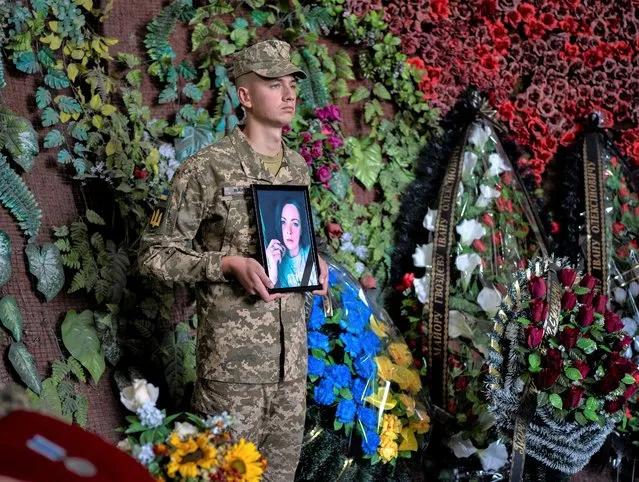 A Ukrainian soldier holds a photo of Olga Simonova, 34, a Russian woman who was killed in the Donetsk region while fighting on Ukraine's side in the war with her native country, in a crematorium in Kyiv, Ukraine, Friday, September 16, 2022. (Photo by Roman Hrytsyna/AP Photo)