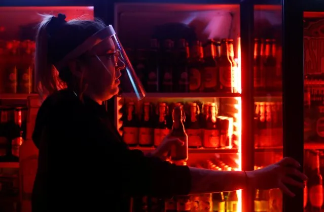 Server Linda Wiegand takes a beer from the fridge of the pub “Die Wache” (The Guard) that reopened today, following weeks of closure due to the global outbreak of the coronavirus disease (COVID-19), in Bonn, Germany, May 11, 2020. (Photo by Wolfgang Rattay/Reuters)