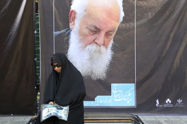A woman attends a funeral ceremony for Iranian prominent poet Houshang Ebtehaj, shown in the posters, in Tehran, Iran, Friday, August 26, 2022. Ebtehaj, a distinguished Iranian poet whose small but influential body of work made him a major figure in his own country and in world literature, died on Aug. 10, at 94, in Cologne, Germany. (Photo by Vahid Salemi/AP Photo)