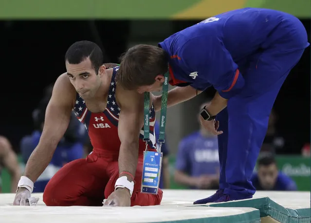 United States' Danell Leyva is assisted by a team official after falling from the horizontal bar during the artistic gymnastics men's team at the 2016 Summer Olympics in Rio de Janeiro, Brazil, Monday, August 8, 2016. (Photo by Julio Cortez/AP Photo)