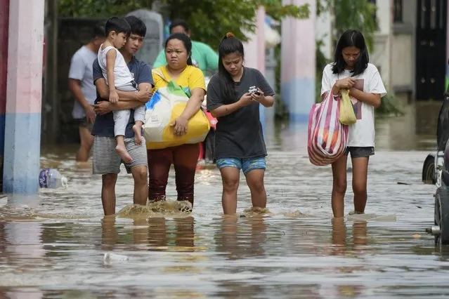 A family evacuates to higher ground as they wade through floodwaters from Typhoon Noru in San Miguel town, Bulacan province, Philippines, Monday, September 26, 2022. (Photo by Aaron Favila/AP Photo)