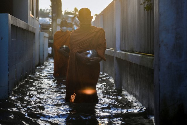 Monks walk to receive alms on a flooded street in Koh Kret in Nonthaburi, in the outskirts of Bangkok, Thailand on October 12, 2022. (Photo by Chalinee Thirasupa/Reuters)