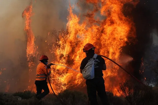 Firefighters try to extinguish a wildfire burning near the village of Kechries, Greece, July 22, 2020. Greek firefighters battled a wind-driven forest fire that burned through pine forest and forced the evacuation of hundreds of people near the seaside village of Kechries in the eastern Peleponnese. (Photo by Costas Baltas/Reuters)