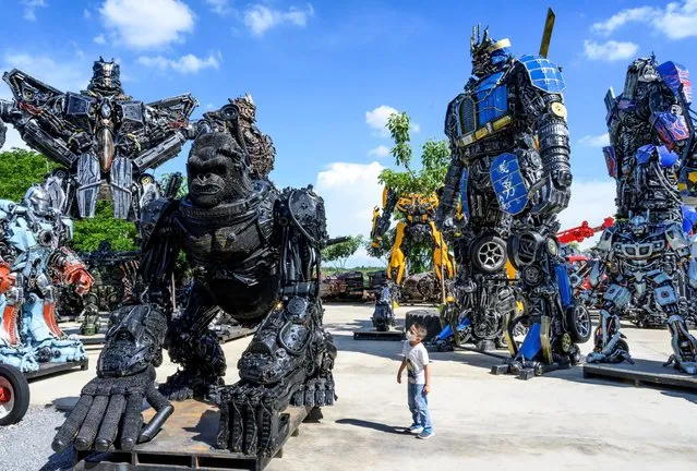This photograph taken on July 18, 2020 shows a child looking at a figure of King Kong in front of life-sized sculptures of characters from the “Transformers” film franchise, all made of scrap metal parts, at the Ban Hun Lek museum in Ang Thong, some 100km north of Bangkok. “Ban Hun Lek” or “The House of Steel Robots” is a museum where a collective of artists display their scrap metal creations depicting popular comics and sci-fi film characters. (Photo by Mladen Antonov/AFP Photo)