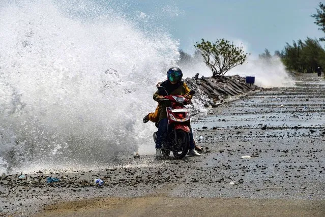 Motorists are hit by large waves breaking on the shores of Banda Aceh on August 3, 2020. (Photo by Chaideer Mahyuddin/AFP Photo)