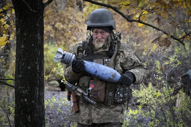 A Ukrainian soldier carries a shell with a written message to the Russian army, in the front line position near Bakhmut, in the Donetsk region, Ukraine, Thursday, October 27, 2022. (Photo by Efrem Lukatsky/AP Photo)