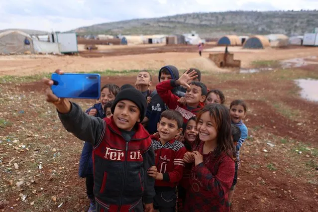 Children pose for a 'selfie' picture at the Kafr Arouk displacement camp in the rebel-held northern countryside of Syria's Idlib province, after heavy rain,on November 25, 2022. (Photo by Aaref Watad/AFP Photo)