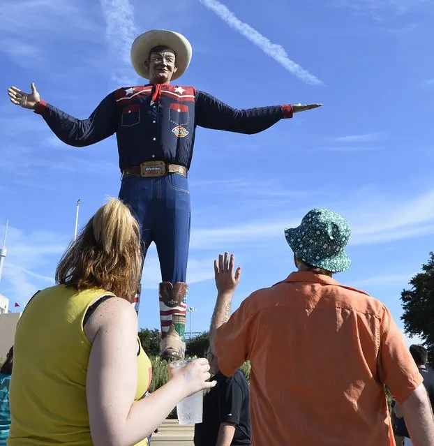 A couple waves to Big Tex while walking on the midway at the State Fair of Texas in Dallas, Texas, USA, 06 October 2015. The State Fair of Texas lasts for three weeks and draws thousands of spectators. (Photo by Larry W. Smith/EPA)