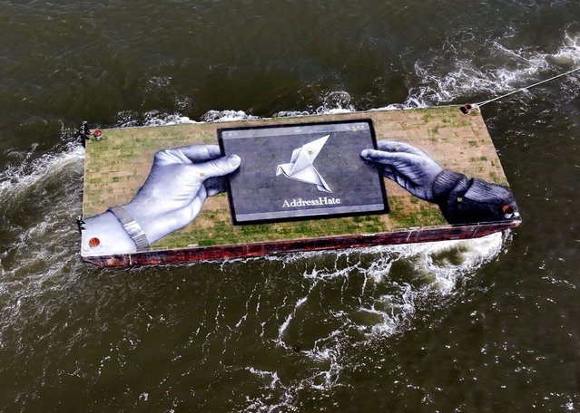 A drone view shows a grass covered barge with a painting installation by Franco-Swiss artist Saype entitled “Address Hate” an initiative that seeks to combat hate speech and promote mutual respect through art, education, and civic dialogue, is towed into New York Harbor in New York City, U.S., May 7, 2025. (Photo by Mike Segar/Reuters)