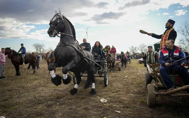 A priest blesses horses and their owners during Epiphany celebrations in the village of Pietrosani, Romania, Friday, January 6, 2023. According to the local Epiphany traditions, following a religious service, villagers have their horses blessed with holy water then compete in a race. (Photo by Vadim Ghirda/AP Photo)