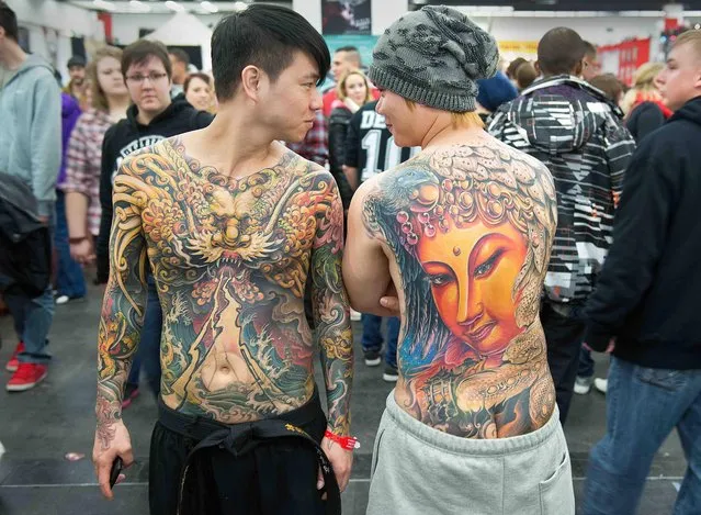 Two young men pose  with their huge tattoos at the International tattoo Convention in Frankfurt, Germany, Saturday March 23,  2013. (Photo by Boris Roessler/AP Photo/Dpa)
