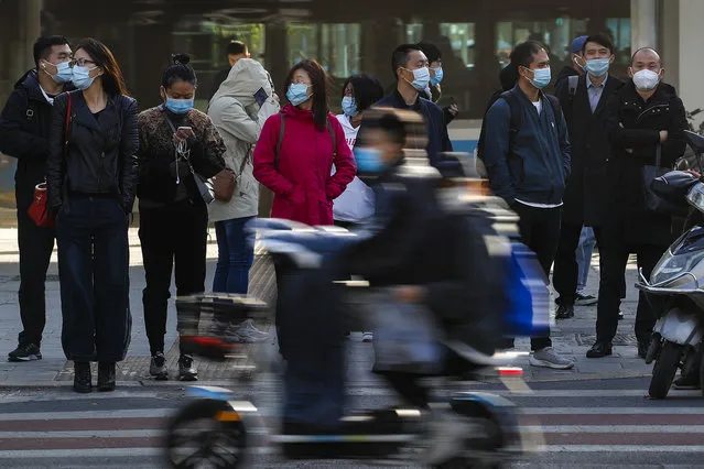 People wearing face masks to help curb the spread of the coronavirus wait to cross a street during the morning rush hour in Beijing, Wednesday, October 21, 2020. (Photo by Andy Wong/AP Photo)