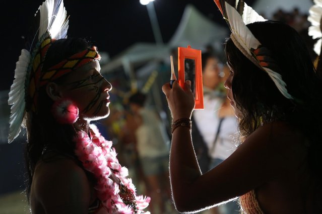 In this photo taken Saturday, October 24, 2015, Brazilian indigenous prepare for a indigenous beauty parade during  World Indigenous Games, in Palmas, Brazil. Rail-thin or thick-waisted, swathed in scarfs and ankle-length skirts or wearing only a thong bikini bottom and bodypaint, they incarnated the cannons of beauty of first peoples from across Brazil and as far afield as Panama and French Guyana. (Photo by Eraldo Peres/AP Photo)